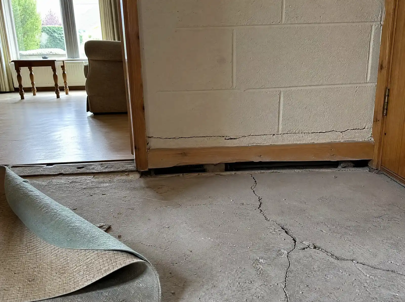 Cracked, lifted floor slab and a crack at the base of an internal wall in a 2000s Irish house