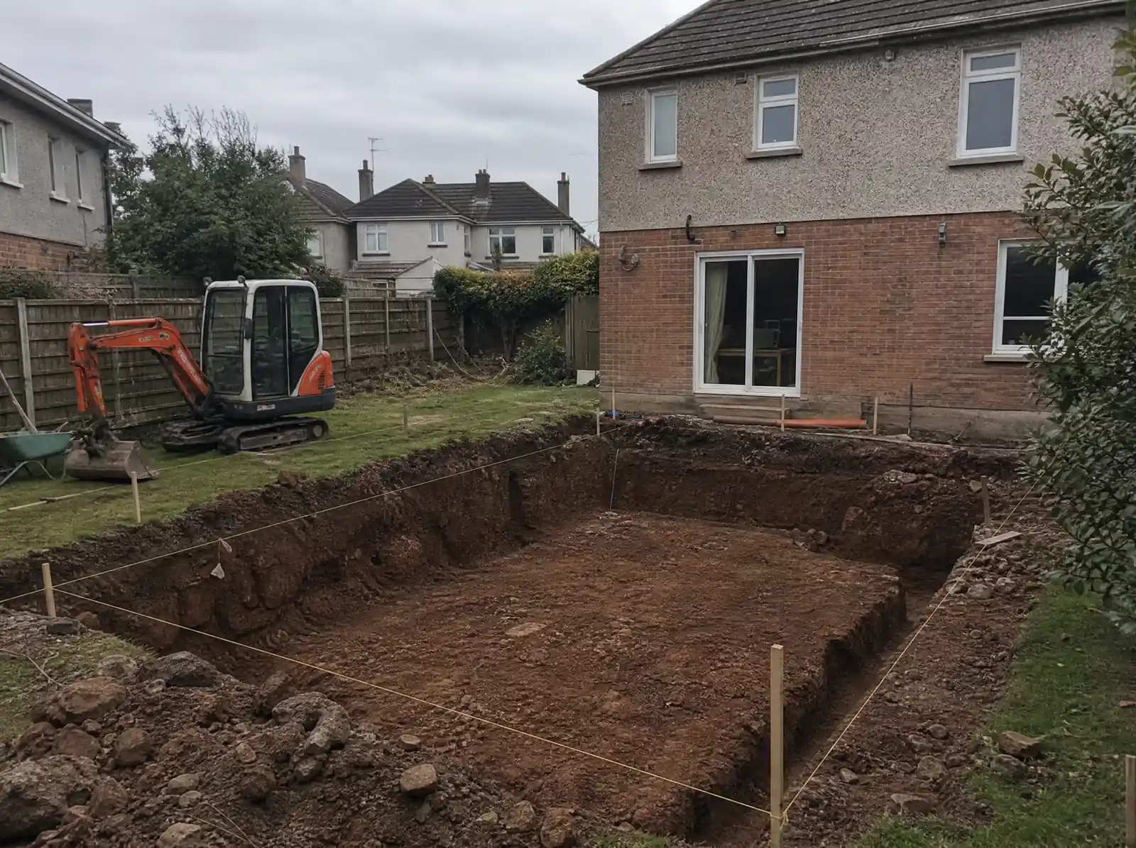 Foundation excavation in boulder clay for a rear extension behind a Dublin semi-detached house, mini digger on the lawn