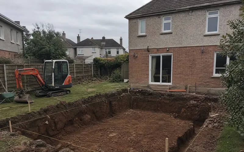 Foundation excavation in boulder clay for a rear extension behind a Dublin semi-detached house, mini digger on the lawn
