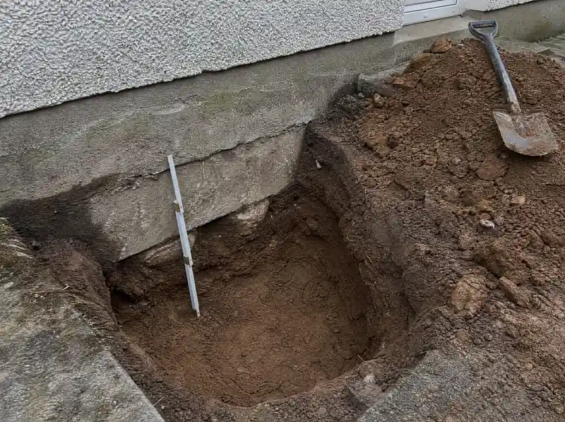 Trial pit exposing a concrete strip foundation and boulder clay beside a Dublin house